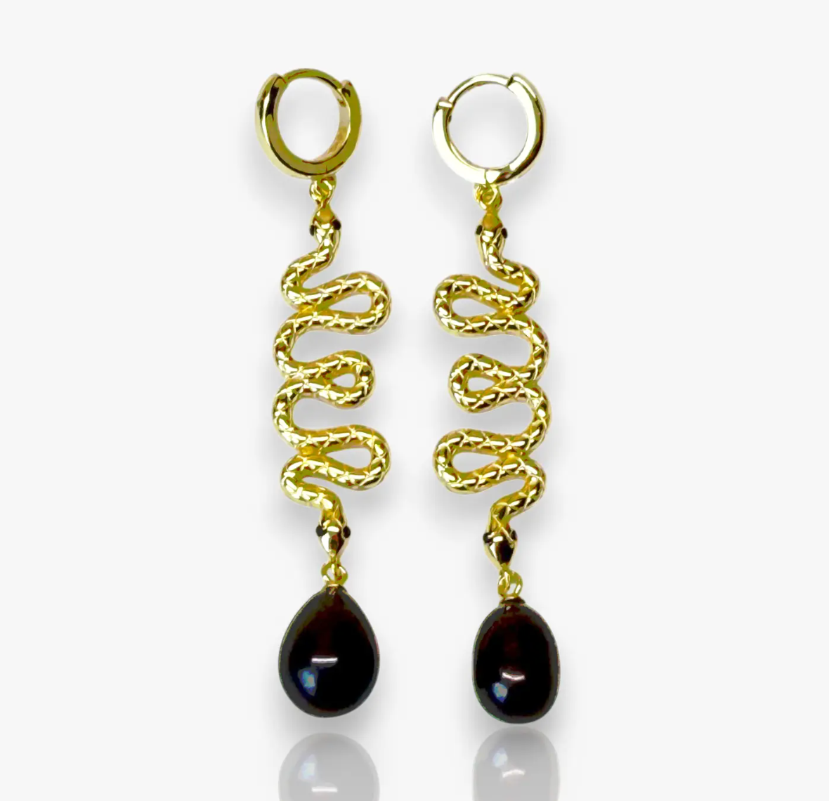 The Serpent Drop Earrings bring a sleek balance of movement and form. Crafted in 14k gold plated over silver, each earring features a sinuous snake design that flows into a dark teardrop pearl. Elegant and commanding, they capture light with every turn, embodying quiet power and refined allure.