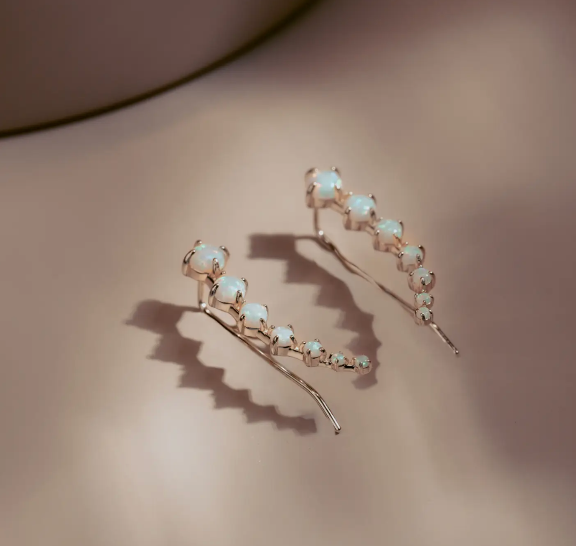 The Opal Arc Climbers follow the natural line of the ear with a graceful curve of glowing opals. Each stone reflects a soft play of color, set in 14k gold plated over silver for a clean polished finish. Refined and modern, they bring quiet radiance to any look.