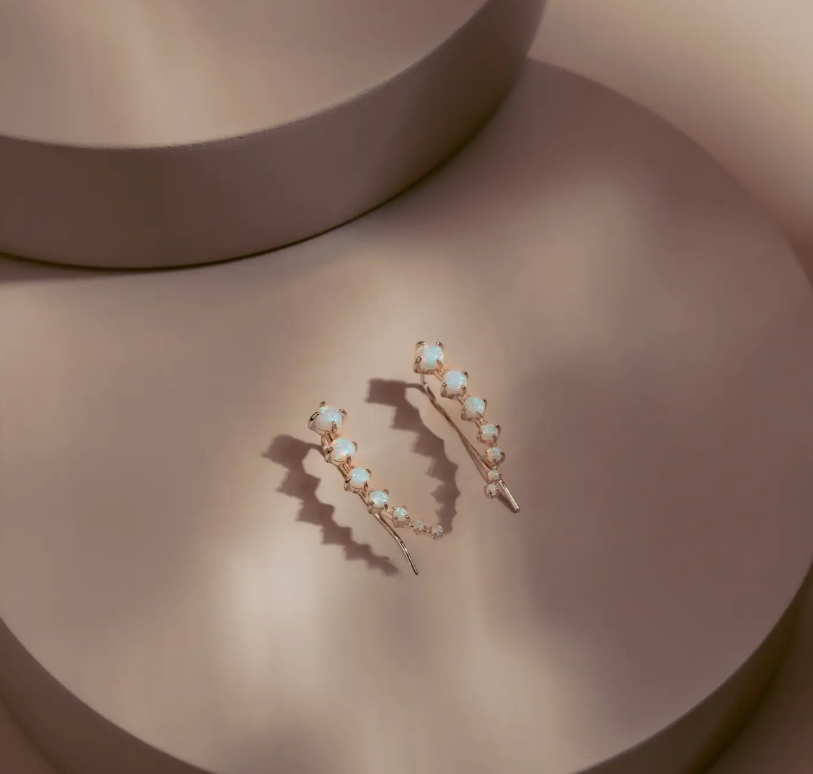 The Opal Arc Climbers follow the natural line of the ear with a graceful curve of glowing opals. Each stone reflects a soft play of color, set in 14k gold plated over silver for a clean polished finish. Refined and modern, they bring quiet radiance to any look.