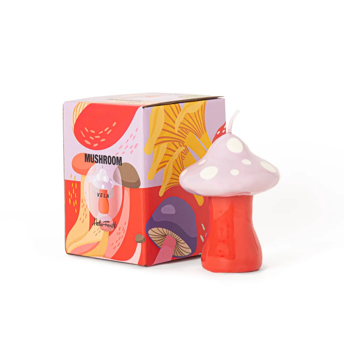 A mushroom-shaped candle in red and pale pink with white spots stands in front of its colorful illustrated product box on a white background.
