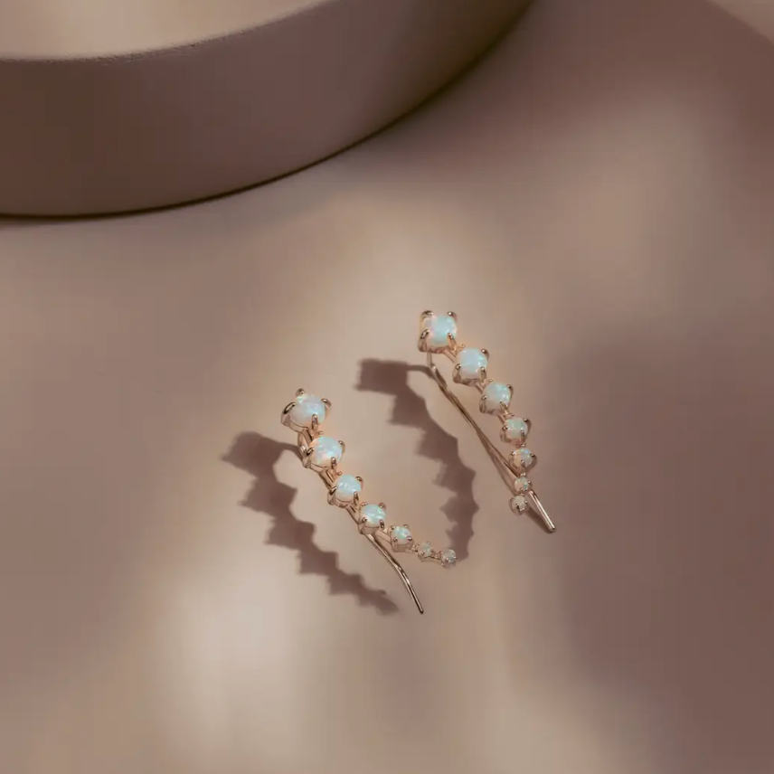 The Opal Arc Climbers follow the natural line of the ear with a graceful curve of glowing opals. Each stone reflects a soft play of color, set in 14k gold plated over silver for a clean polished finish. Refined and modern, they bring quiet radiance to any look.