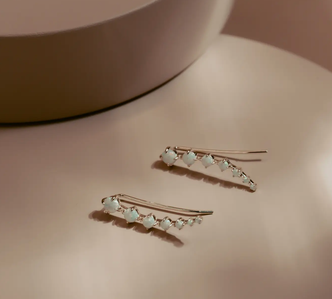 The Opal Arc Climbers follow the natural line of the ear with a graceful curve of glowing opals. Each stone reflects a soft play of color, set in 14k gold plated over silver for a clean polished finish. Refined and modern, they bring quiet radiance to any look.
