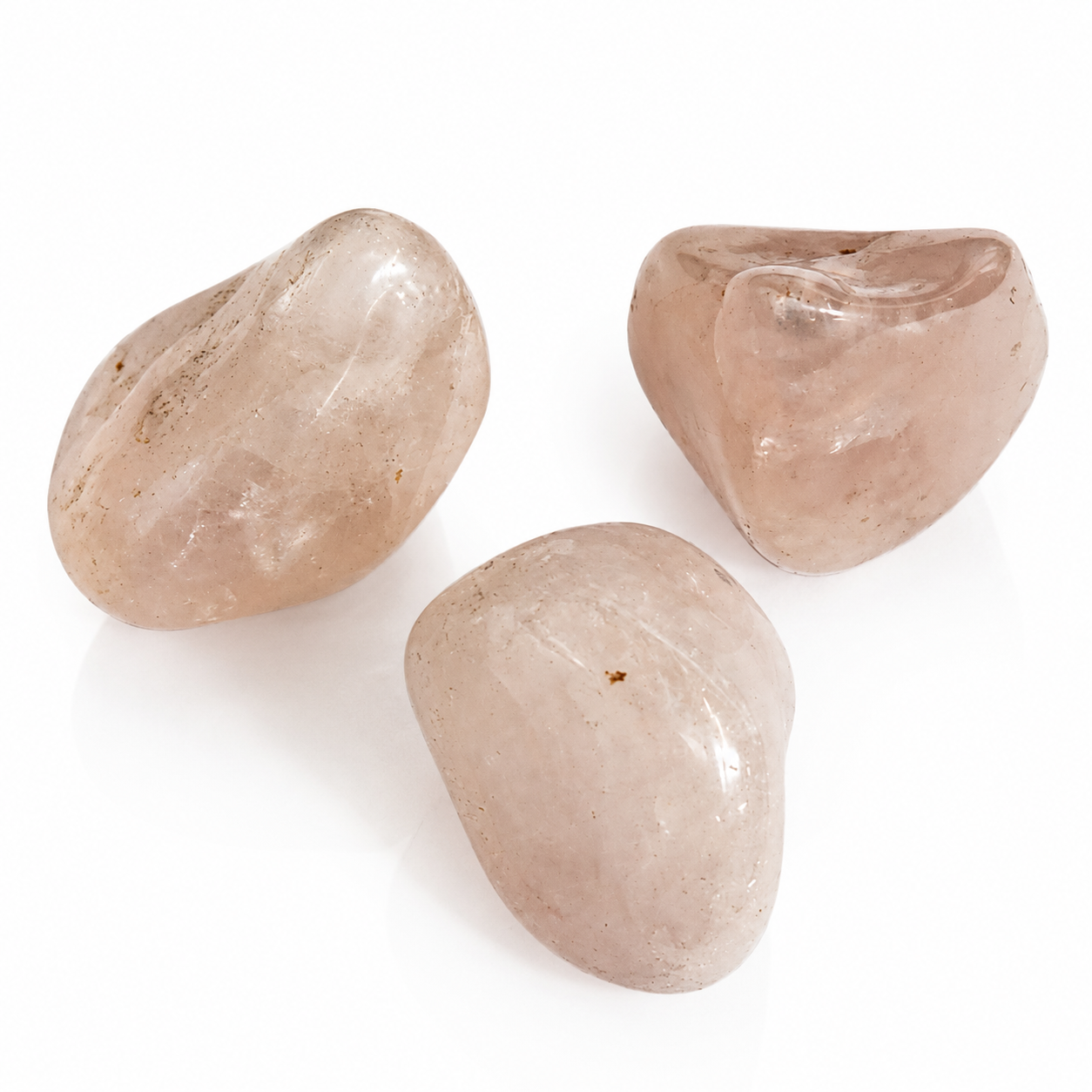 Three smooth, polished rose quartz crystal stones arranged on a clean white background.